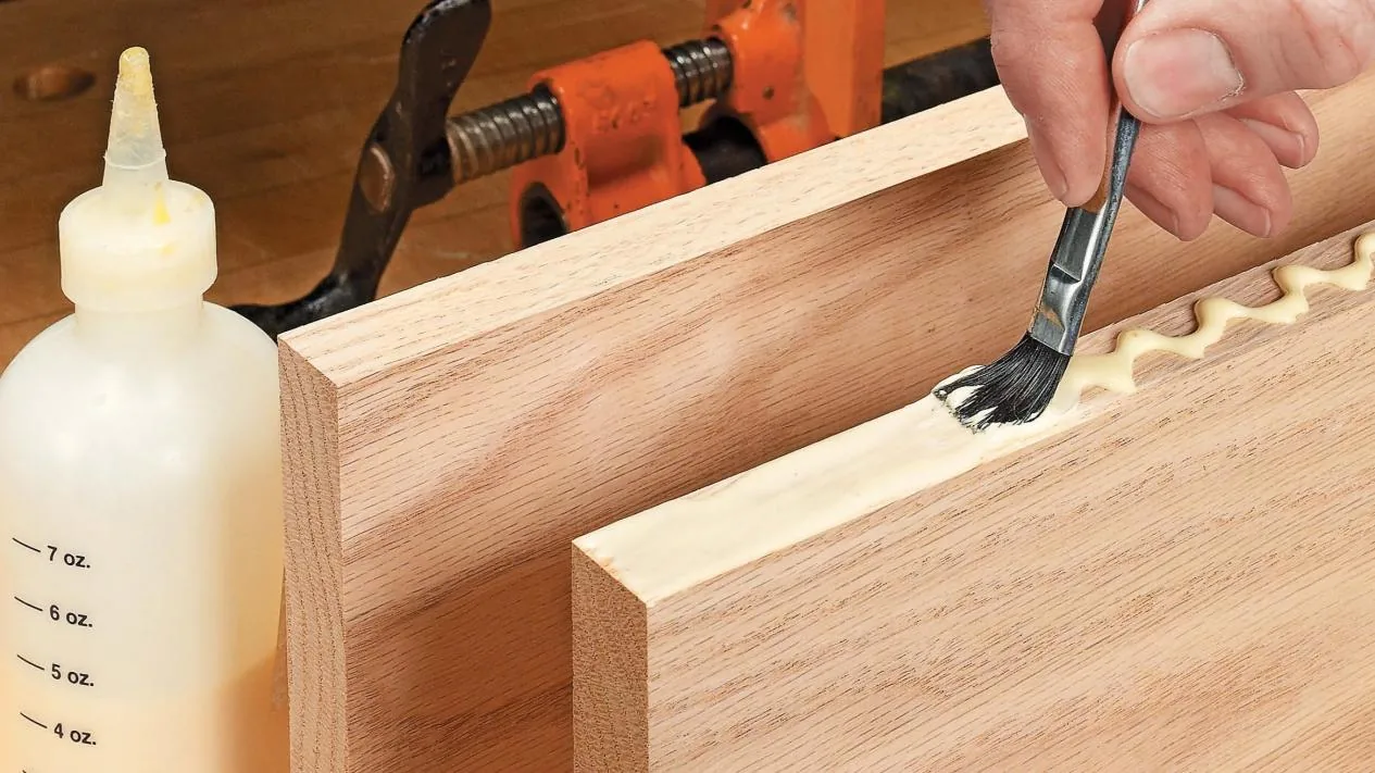 Craftsman applying PVA wood adhesive on solid wood furniture joint