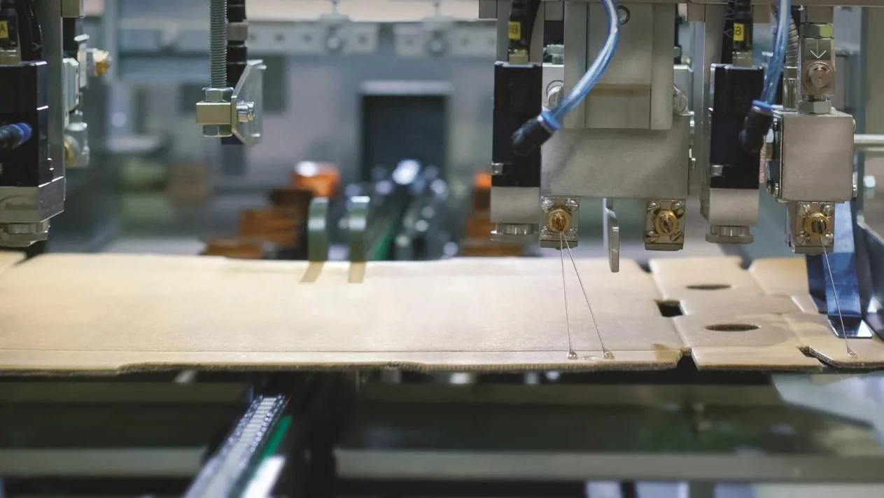 High-speed packaging line applying water-based film lamination adhesive on corrugate board